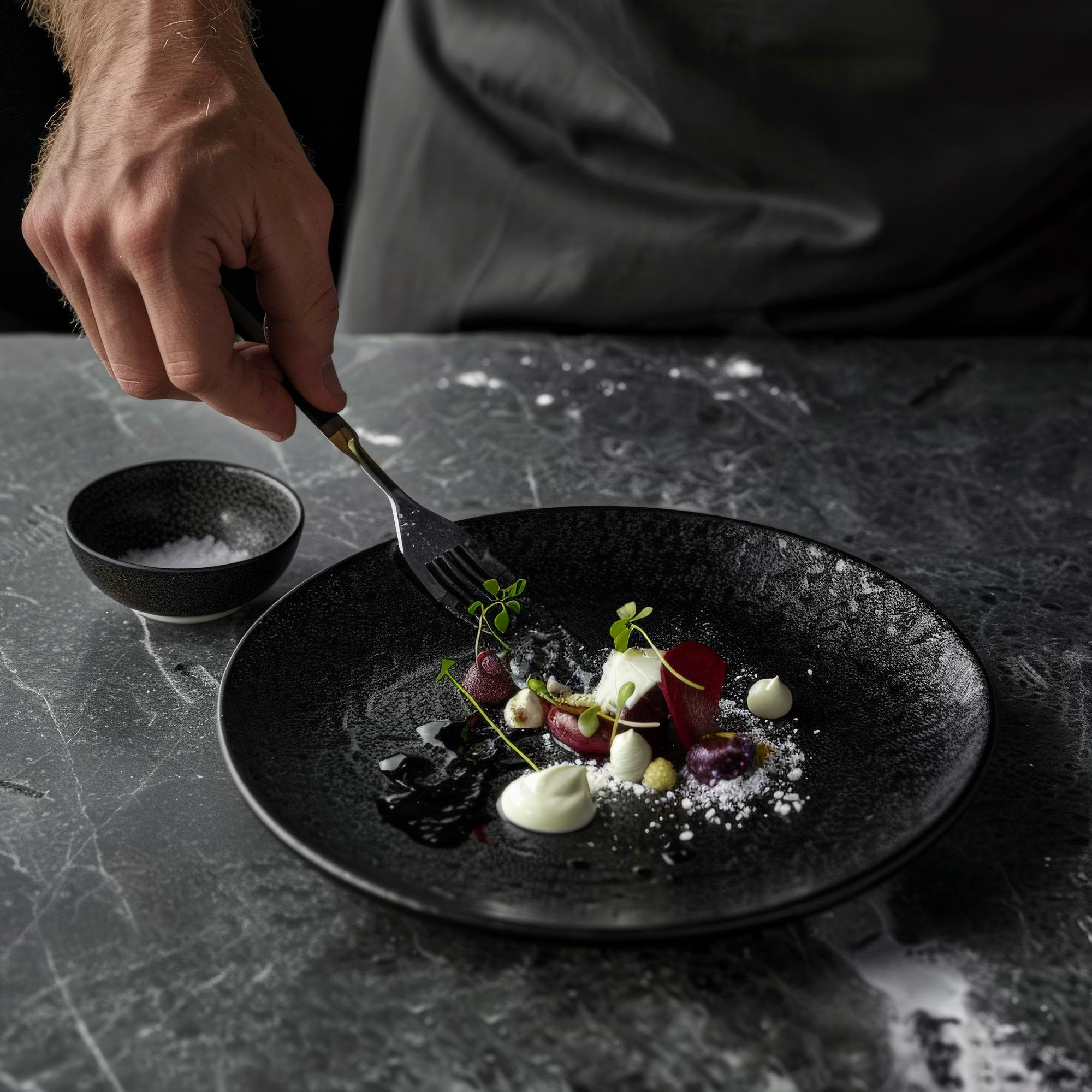 Chef demonstrating plating on a dark table